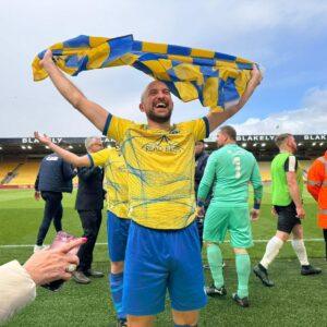 Massive celebrations at Carrow road player holding a checked blue and yellow flag for Norton Athletic